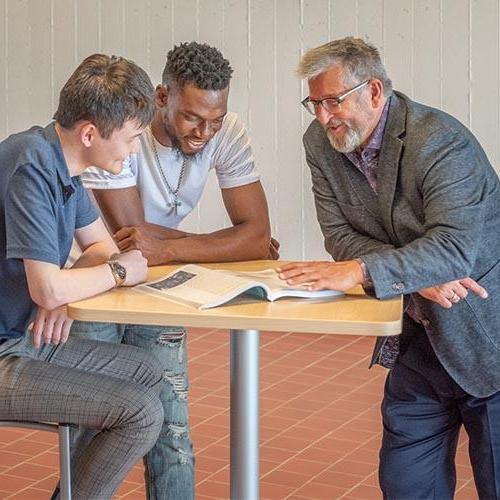 Dr. Karel Sovak meeting with two male students.