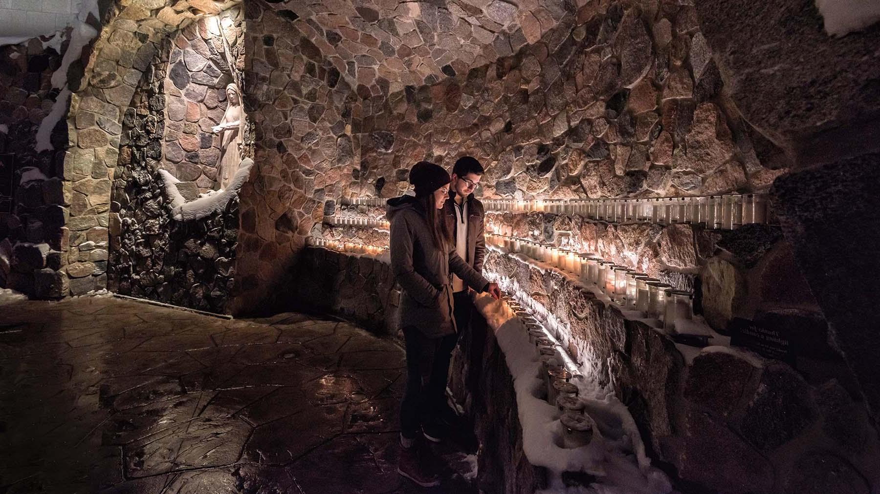 Two students lighting a candle in the grotto 